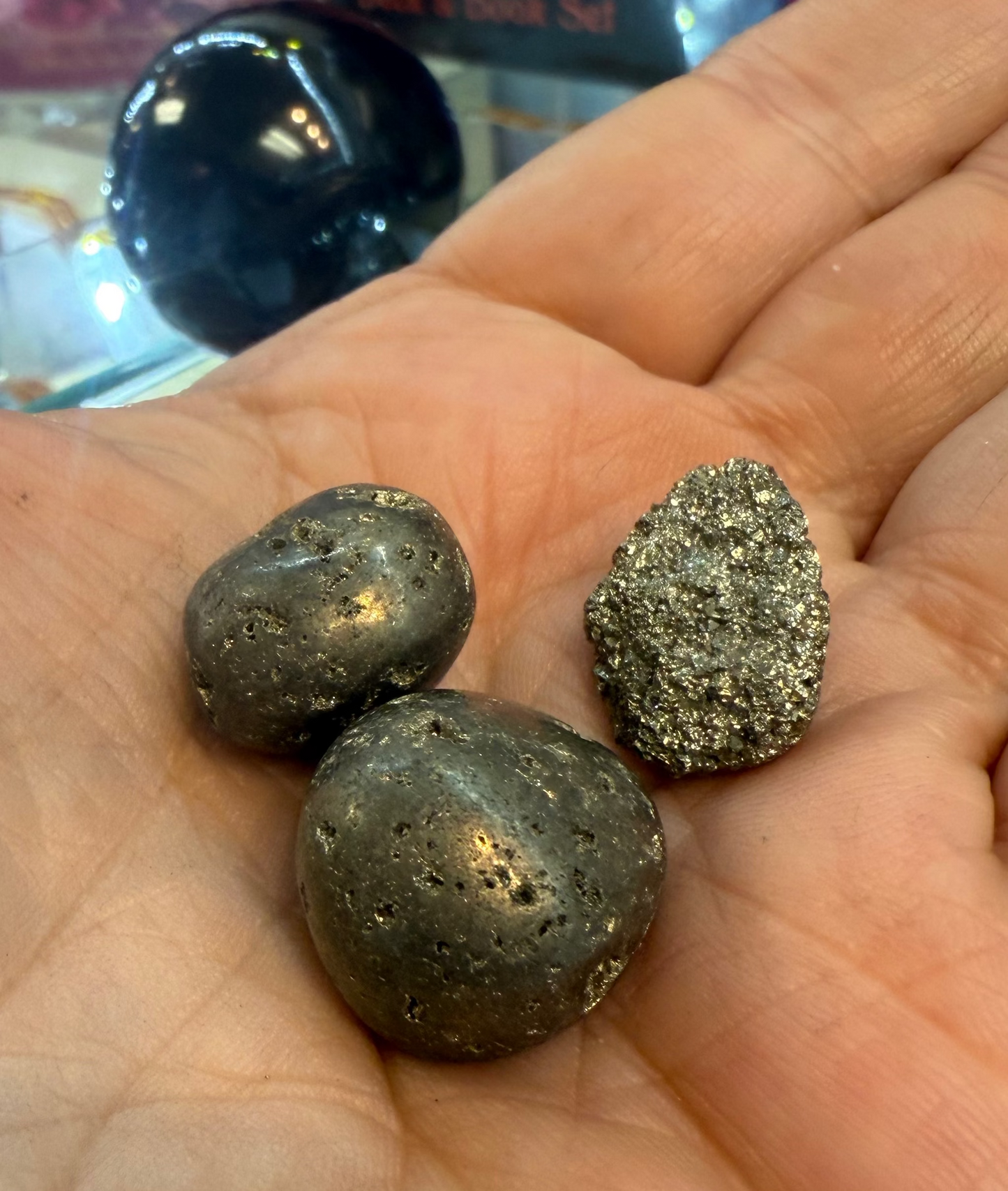 Three metallic stones held in a hand with a blurred background